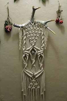 an art piece made out of yarn with horns and chains hanging from it's sides