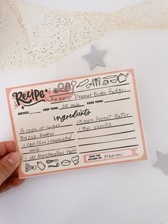 a person holding up a recipe card in front of some confetti and stars