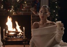 two women sitting in front of a fire place with candles and blankets on their shoulders