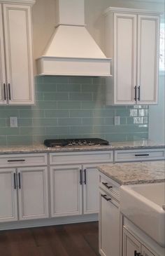 a kitchen with white cabinets and marble counter tops