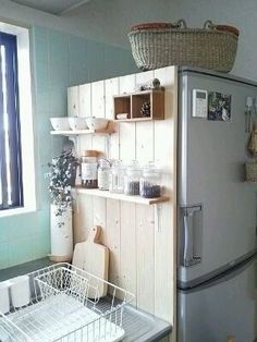 a kitchen with a refrigerator, dishwasher and shelves on the wall above it