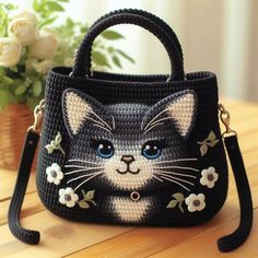 a crocheted purse with a cat on the front and flowers on the side