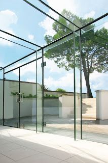 an empty room with glass walls and a tree in the background