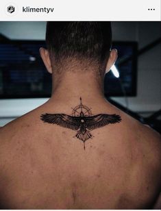 the back of a man's neck with a black bird tattoo on his chest