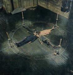 an old black and white photo of a woman laying on the floor in front of a clock