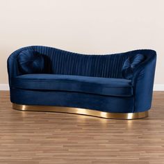 a blue couch sitting on top of a hard wood floor next to a white wall