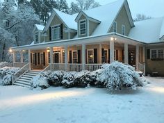 a house covered in snow with lights on the porch and steps leading up to it