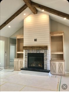 an empty living room with a fireplace and built - in bookshelves