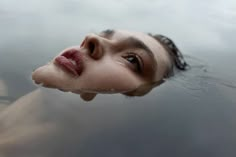 a woman is floating in the water with her eyes open