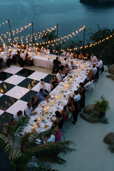 a long table with people sitting at it and lit candles on the tables in front of them