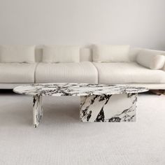 a marble coffee table sitting on top of a white carpeted floor next to a couch