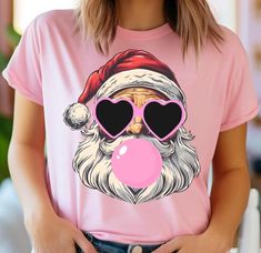 Retro Santa Christmas Blowing Bubble T-shirt, Red Santa Shirt, Pink Santa Shirt,Christmas Vintage Pink Christmas,Santa With Sunglasses Shirt 📢Please Check All Photos For Details.   📢Choose Your T-Shirt Size From The Drop-Down Lists Next To The item Picture   📢Choose Of Your T-Shirt Color From The 2nd Picture 🧨Please contact the store for long-sleeved shirt and sweatshirt color options. 🧨Please check which product you are paying for in the size options section, because there are different options such as short-sleeved shirts, V-Neck, sweatshirts and long-sleeved shirts. 📢Use "Add message to Seller" link On The Checkout Page To Send me the Following important Details For Your Order's Customization.   📢Shipping Time Varies by location (we are located in Sugar Land, Texas) please consid Pink Crew Neck T-shirt For Holidays, Pink Graphic Print Christmas Tops, Pink Santa Shirt, Cute Pink Christmas T-shirt, Vintage Pink Christmas, Santa Tee, Pink Santa, Santa Shirt, Retro Santa