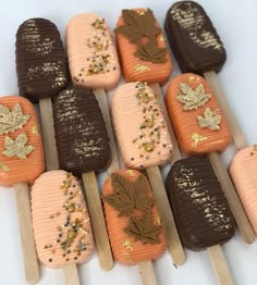 there are many ice creams on sticks decorated with gold leaf designs and maple leaves