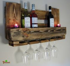 wine glasses and bottles are sitting on a wooden shelf with candles in the bottom half