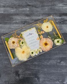 an arrangement of flowers on a table with a wedding card in the center and gold frame