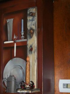 a wooden shelf with plates and silverware on it, next to a wall hook