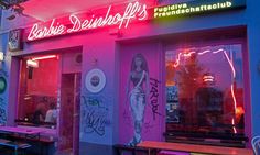 the outside of a restaurant with neon lights and graffiti all over it's walls