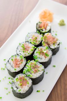 sushi is served on a white plate with green garnish