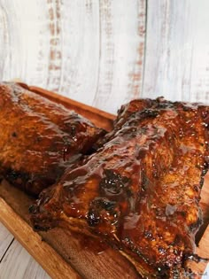 two ribs covered in bbq sauce sit on a cutting board