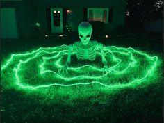 a skeleton sitting in the grass with green lights on it's face and hands