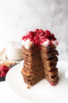 a stack of pancakes topped with whipped cream and raspberry toppings on a white plate