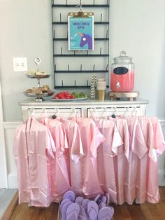 several pairs of pink slippers sitting on top of a wooden floor next to a table