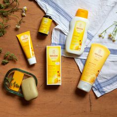 various sunscreens and body lotions laid out on a wooden table next to a towel