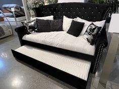 a black and white couch sitting on top of a floor next to a bed with lots of pillows