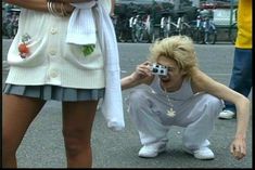 a woman taking a photo with her camera in front of a man on the street