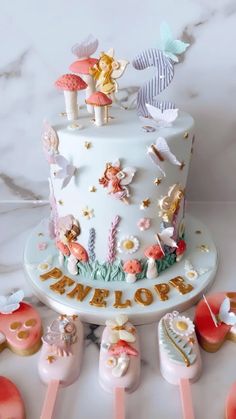 there is a white cake decorated with pink and gold decorations on the top, surrounded by little toys