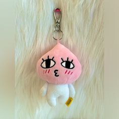 a pink and white stuffed animal keychain with eyes