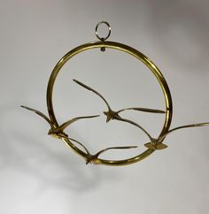 a metal bird decoration hanging from a hook on a white wall in the shape of a circle