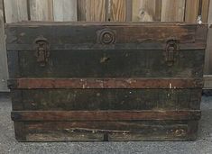 an old wooden trunk sitting in front of a fence