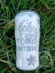 a glass jar that says baby it's cold outside on the grass with snowflakes