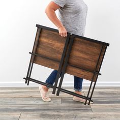 a woman holding a wooden sign on top of a hard wood floor