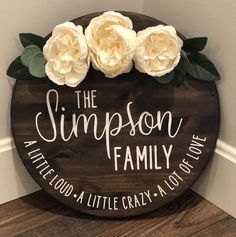 a wooden sign that says the simpson family with three white roses on top of it