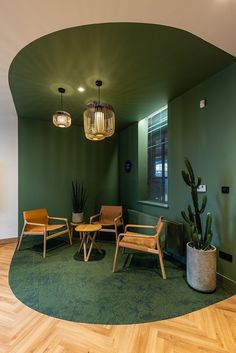 a room with green walls and wooden chairs in the corner, two potted plants on either side