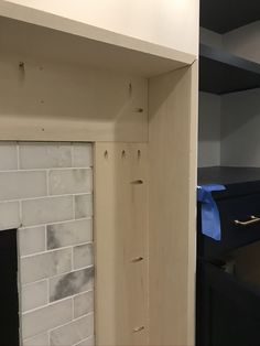 an empty room with a white brick fireplace and black shelves on the wall next to it