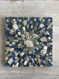 a blue and green mosaic tile on a white wooden surface with a circular hole in the center