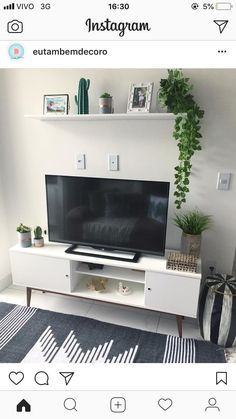 a flat screen tv sitting on top of a white entertainment center next to a potted plant