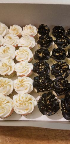 a box filled with lots of different types of cupcakes on top of a wooden table