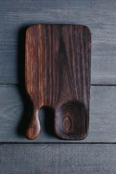 a wooden cutting board sitting on top of a gray wood floor next to a knife