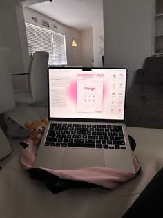 an open laptop computer sitting on top of a table next to a stuffed animal bear