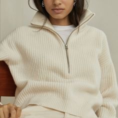 a woman sitting on a chair wearing a white sweater