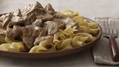 a plate full of pasta with meat and sauce on the side next to a fork