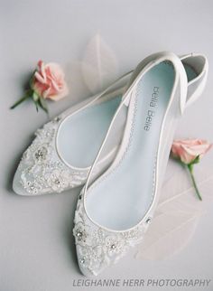 a pair of white shoes sitting on top of a table next to pink flower bouquets