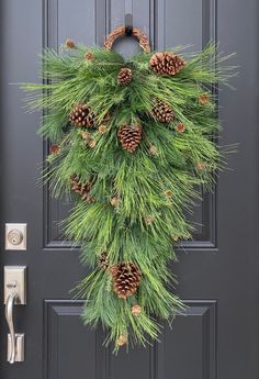 a pine cone wreath hangs on the front door with evergreen needles and cones around it