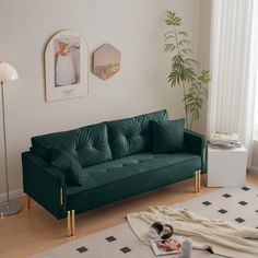 a living room with a green velvet couch and white rug on the floor next to a window