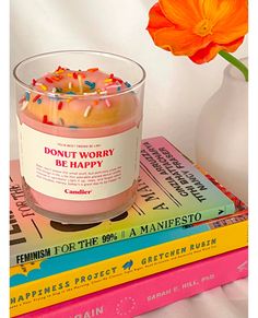 a candle sitting on top of three books next to a flower