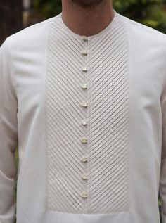 Hits mid-thigh Round neckline Front button opening with self-fabric loops Chevron-style pleats on front placket Side slits Model is 184cm (6 feet) and wearing size L. Item Code: mQ0561 Mens Kurta Stitching Design, Kurta Type Shirt For Men, Men Kurta Designs Style 2024, Men Kurta Collar Design, Side Button Kurta For Men, Kurta Piping Pattern Mens, Boy Kurta, Panjabi Design, Man Dress Design